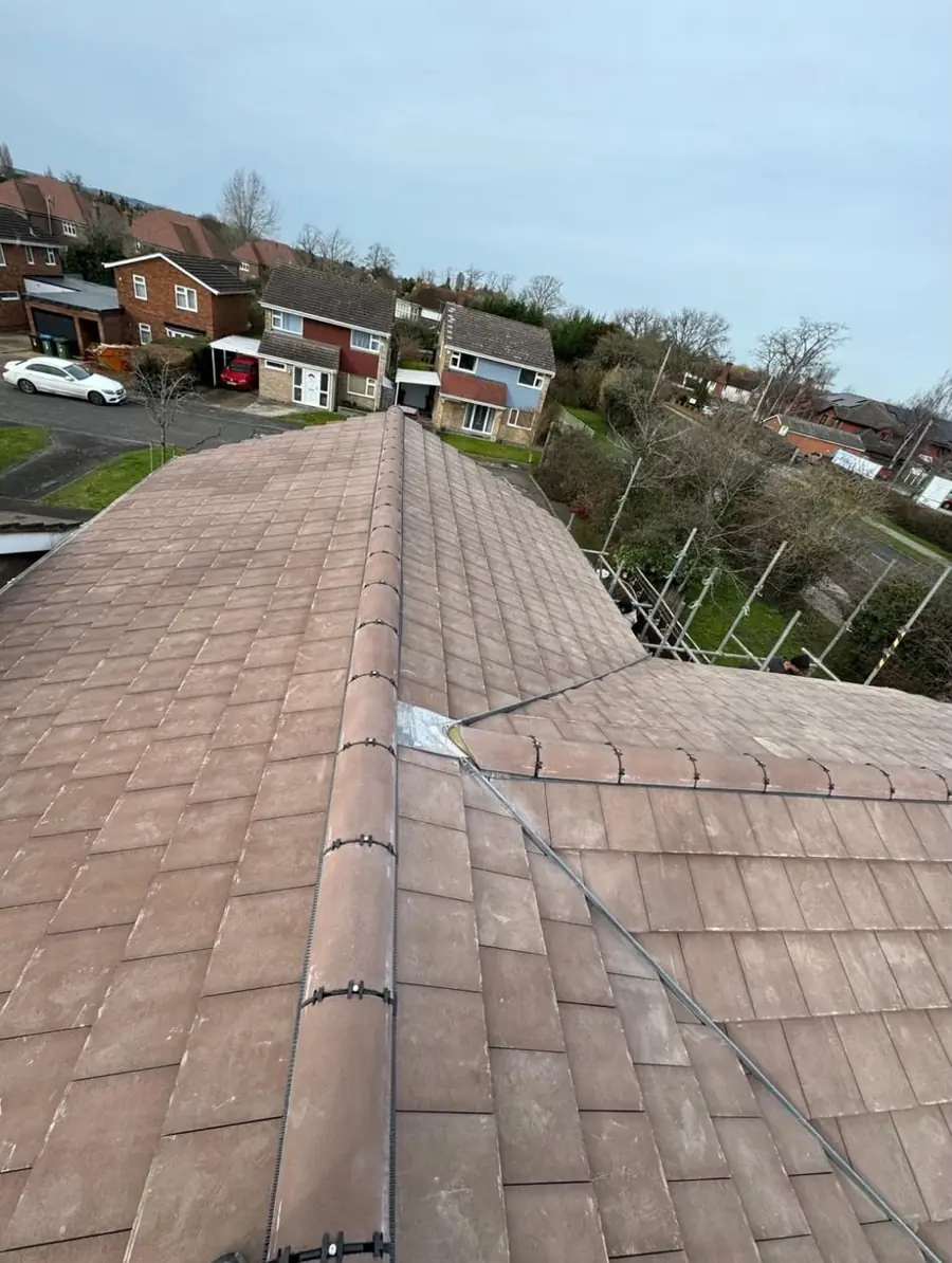 Brown tiled hip and ridge with a lead flashing patch, houses and street beyond