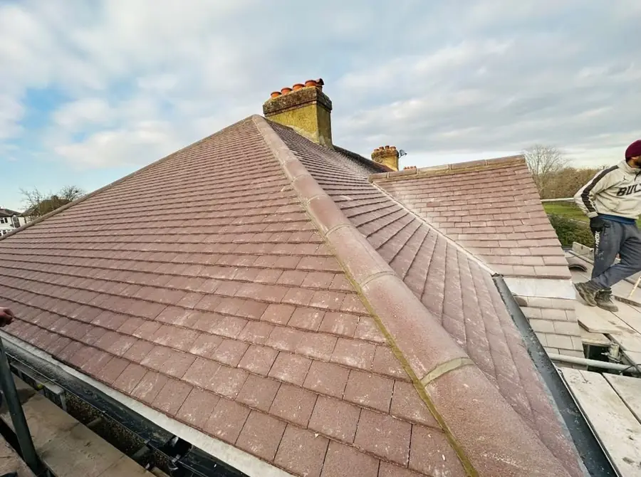 Brown tiled hip roof with a ridge and chimney, scaffold along the eaves