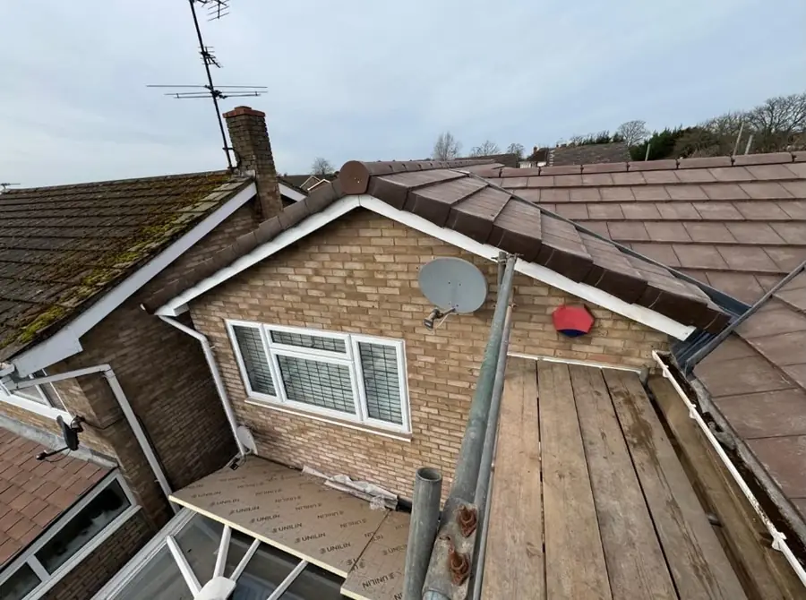 Brown tiled roof and a brick dormer with a bay window below, scaffold boards at the eaves, seen from the roof