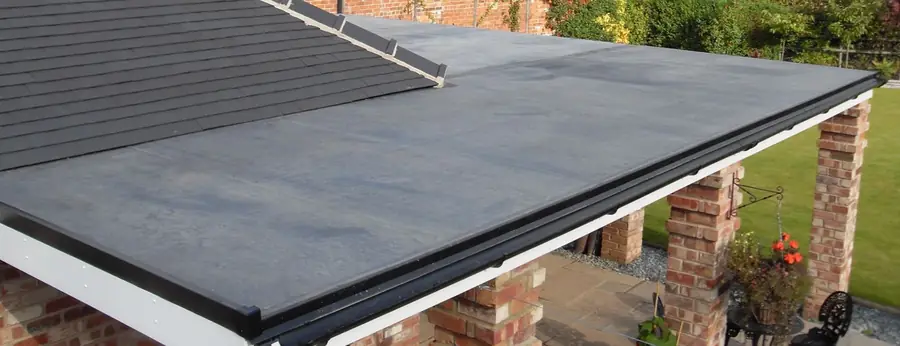 Dark flat roof with a white fascia over a covered patio on brick pillars