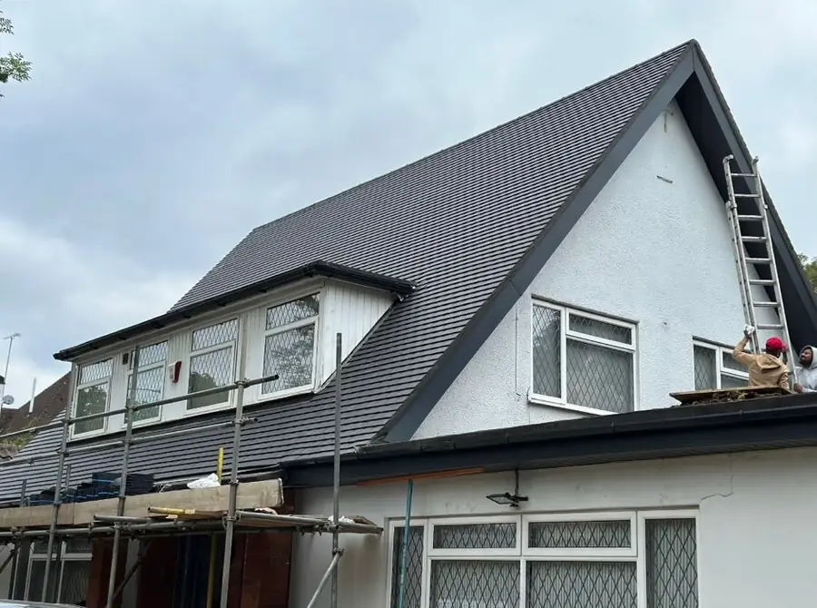 Dark tiled gable roof on a white rendered house with a dormer, scaffold at the eaves