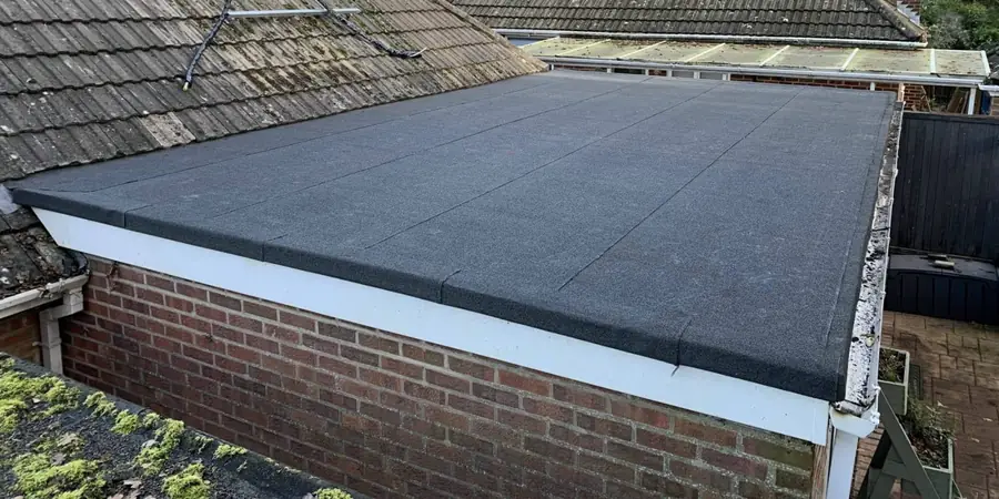 Finished felt flat roof with a white fascia above a brick wall