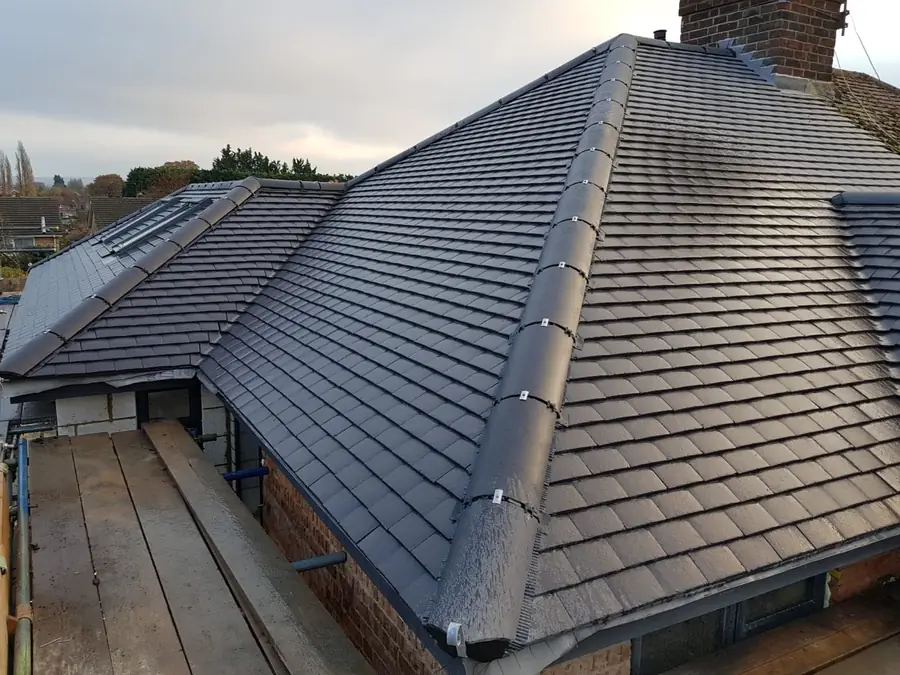 Finished grey tiled hip roof on a bungalow, scaffold round the eaves