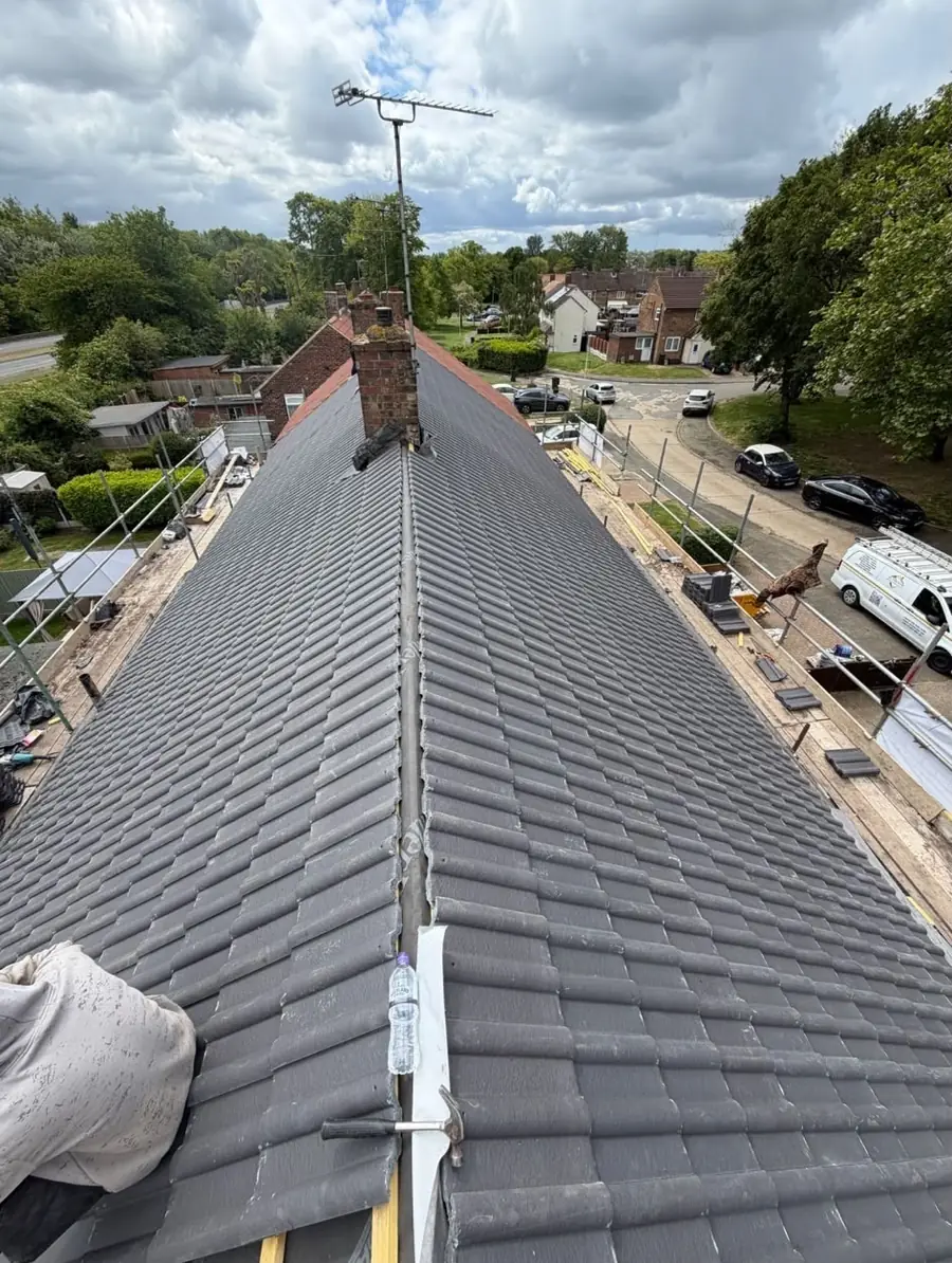 Grey tiled ridge running away to a brick chimney with a TV aerial, scaffold and a van below