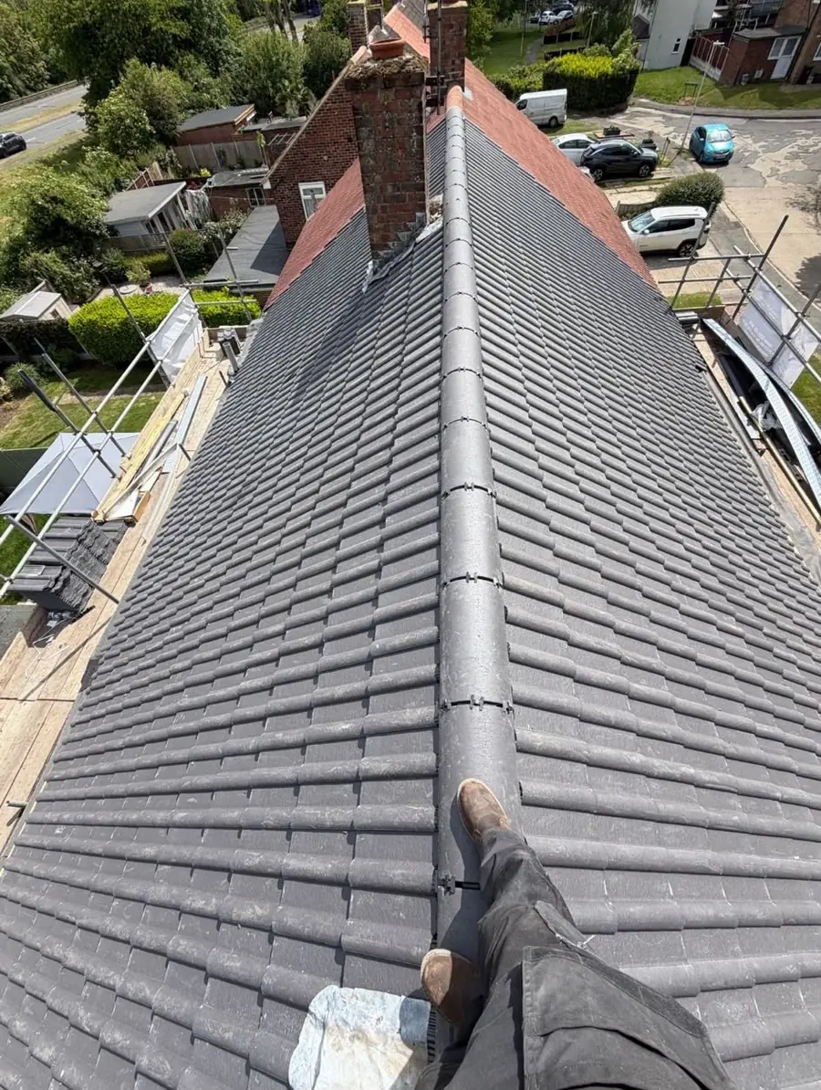 Grey tiled roof with a ridge running up to a brick chimney, scaffold along the edge