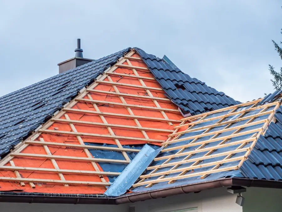 Hip roof half re-tiled with orange membrane and battens exposed