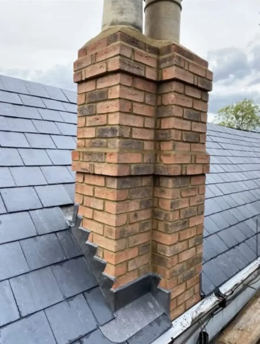 Twin brick chimney stack on a slate roof with stepped lead flashing