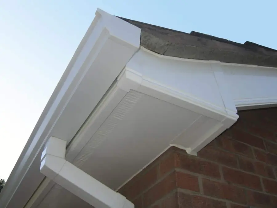 White fascia, vented soffit and gutter running round a brick corner, seen from below
