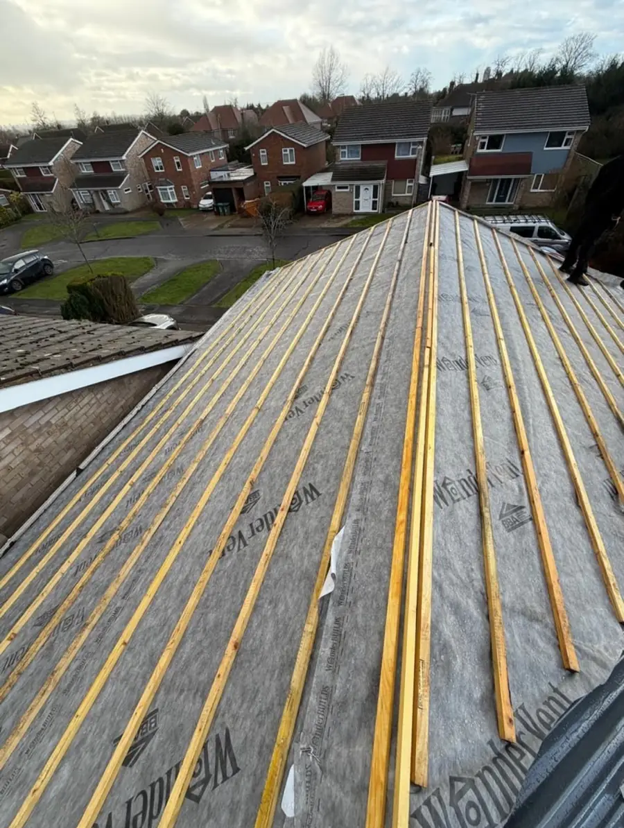 Roof slope with membrane and yellow battens, an estate of houses beyond